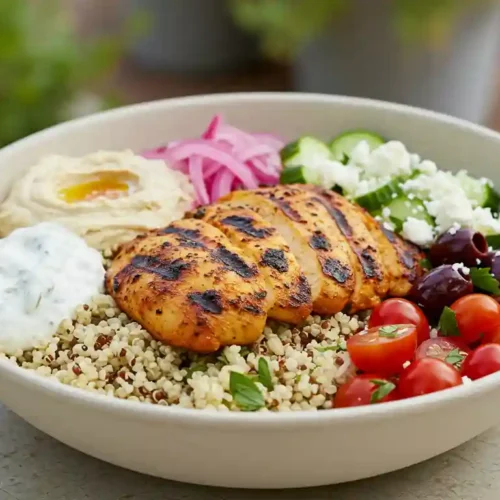 Realistic image of a Cava Harissa Chicken Bowl with grilled chicken, quinoa, rice, hummus, tzatziki, and fresh vegetables.