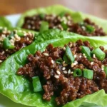 Fresh Korean Ground Beef Lettuce Wraps with sesame seeds and green onions on white plate in a modern kitchen