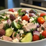 Fresh Mediterranean Tuna Salad Recipe with tuna, vegetables, olives, feta, and olive oil in a modern kitchen.