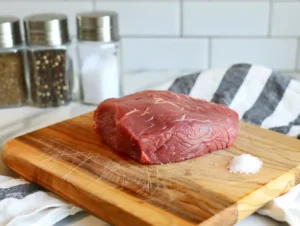 Raw sirloin steak being patted dry with paper towels and seasoned for teriyaki beef steak recipe