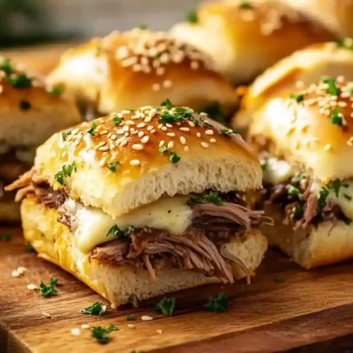 Irresistible French Dip Sliders: The Perfect Party Snack! 6 Close-up of freshly made French Dip sliders with roast beef, provolone cheese, and a dipping sauce in a cozy kitchen setting.