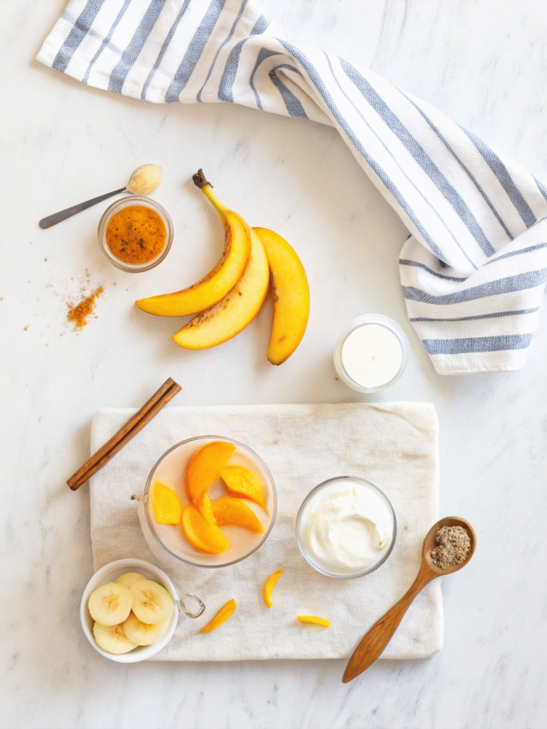 Creamy Peach Smoothie (No Sugar Needed) 2 Flat lay of peach smoothie ingredients on marble with bananas, yogurt, cinnamon