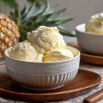 Bowl of creamy pineapple ice cream with fresh pineapple and mint garnish