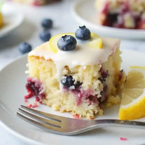 Lemon Blueberry Sheet Cake Recipe 7 A close-up of lemon blueberry sheet cake showing blueberries inside and glaze dripping on top