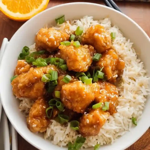 Easy Gluten-Free Orange Chicken (Better Than Takeout!) 4 Overhead view of gluten-free orange chicken served on white rice with scallions in a white bowl