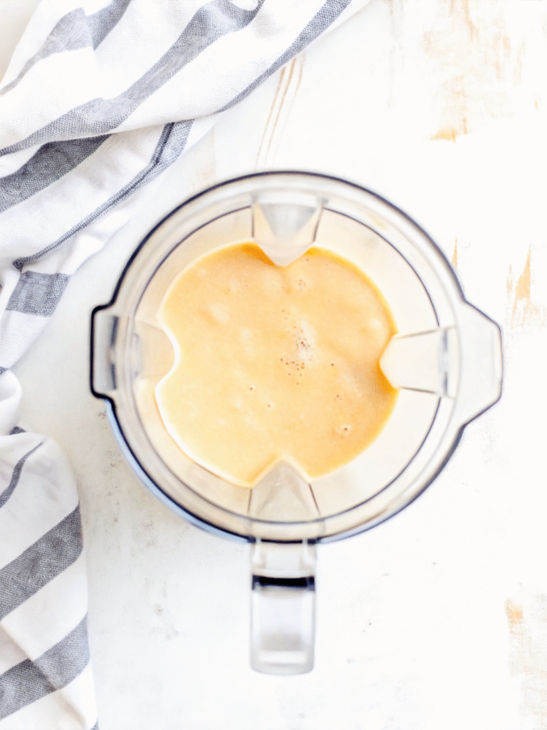 Creamy Peach Smoothie (No Sugar Needed) 4 Freshly blended peach smoothie in a glass blender on white marble
