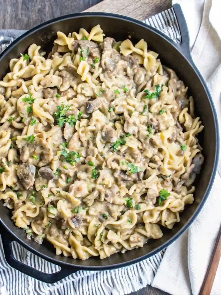 Ground Beef Stroganoff Recipe 1 Top view of creamy ground beef stroganoff with noodles and herbs in a skillet