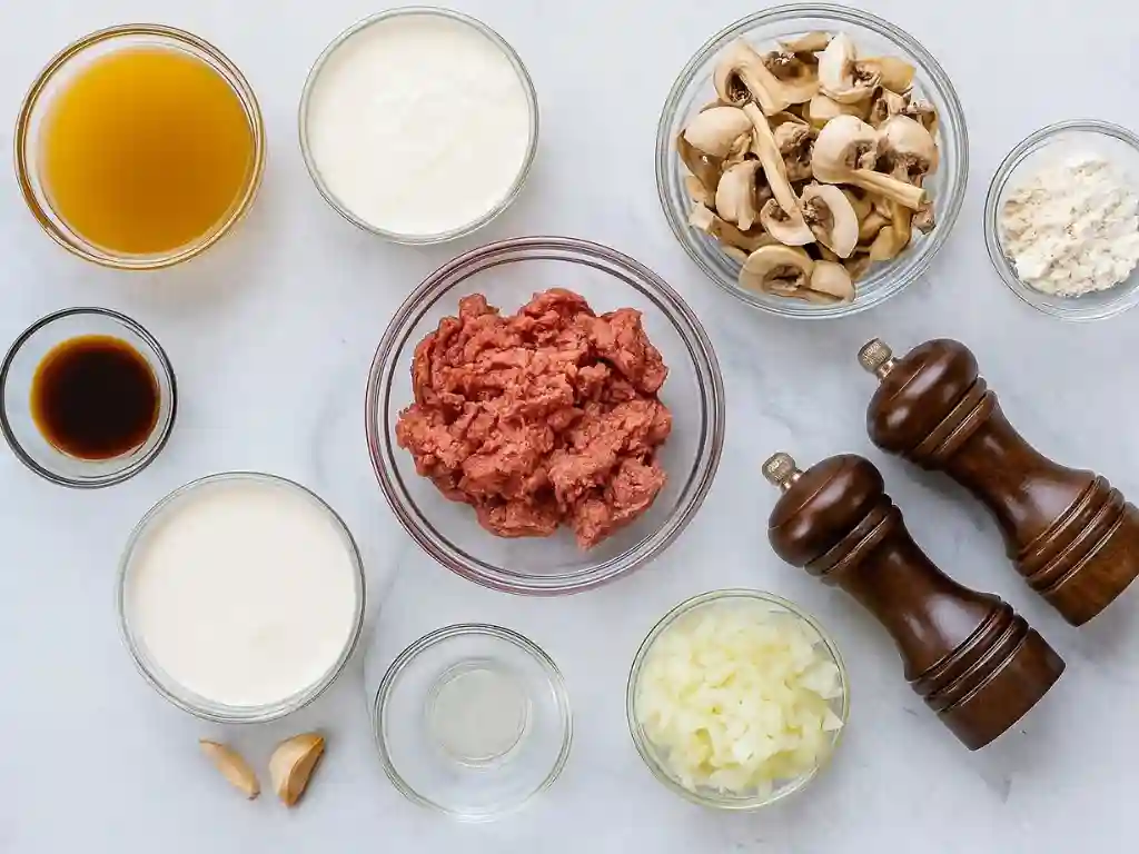 Ground Beef Stroganoff Recipe 2 Flat lay of ground beef stroganoff ingredients including beef, mushrooms, cream, onion, and spices