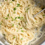 creamy garlic parmesan pasta in a skillet with fresh herbs