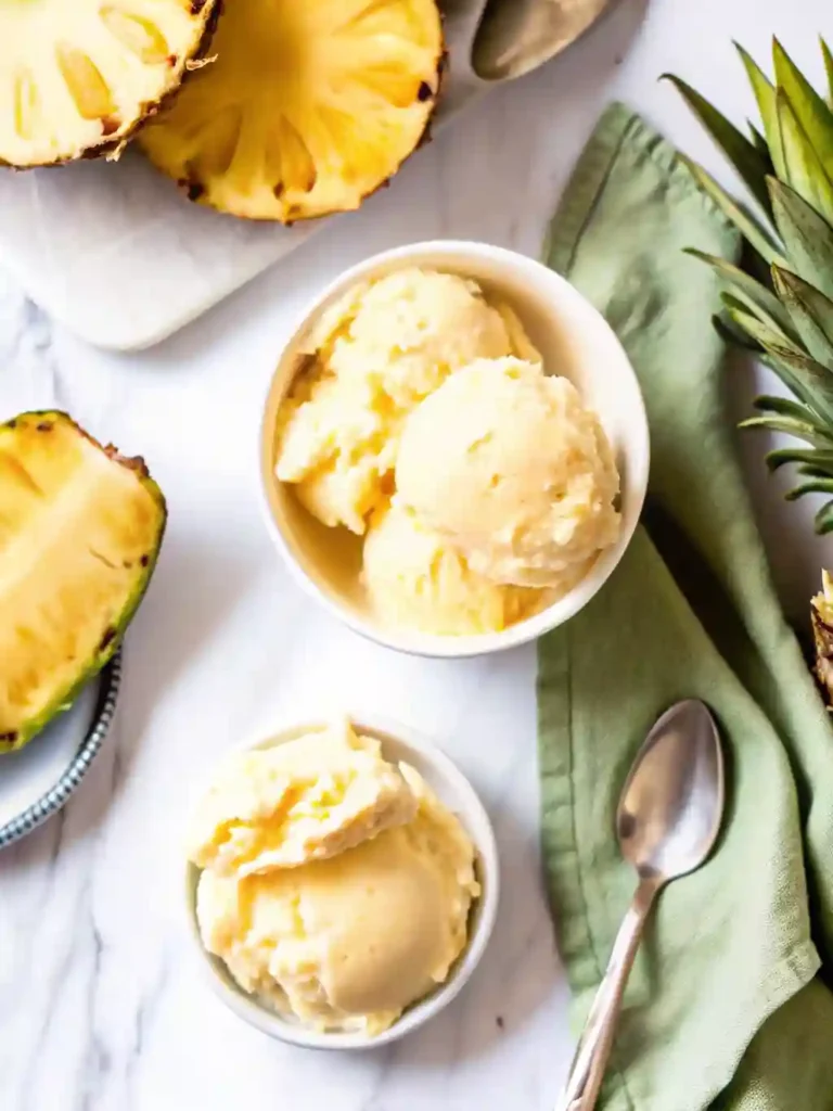 5-Star Pineapple Ice Cream Recipe You'll Crave 3 Two bowls of pineapple ice cream with fresh pineapple and green napkin