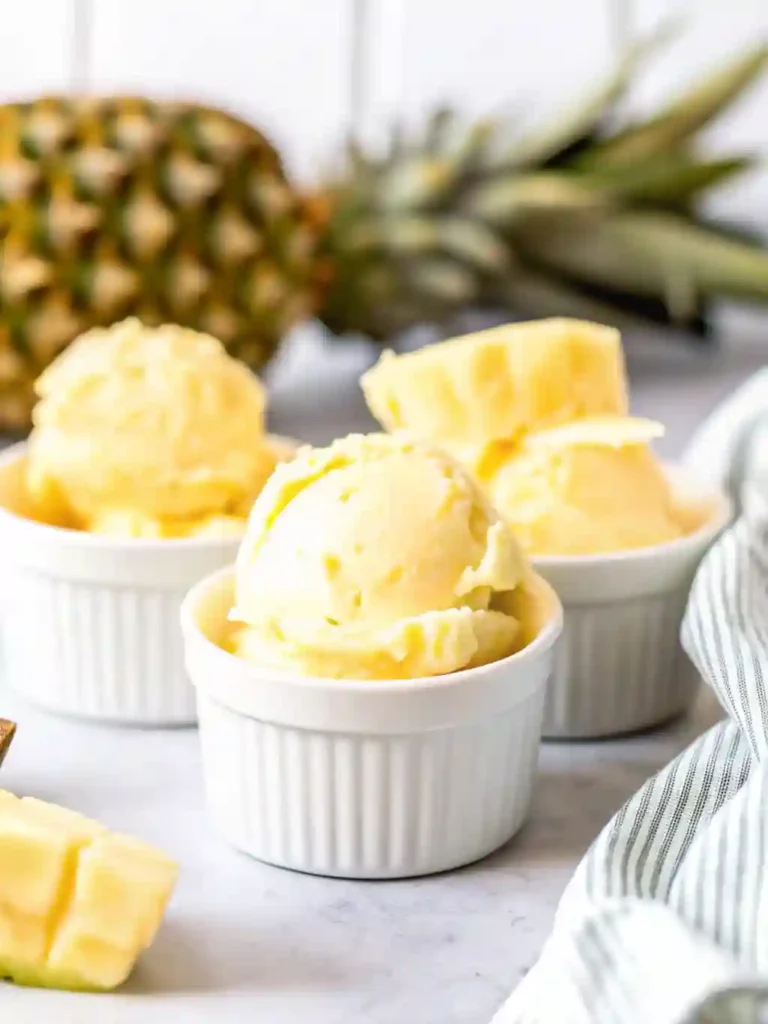 5-Star Pineapple Ice Cream Recipe You'll Crave 8 Creamy pineapple ice cream scooped into white ramekins with fresh pineapple chunks