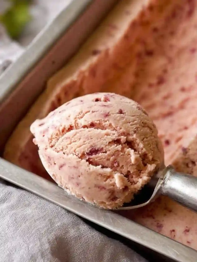 The Best Homemade Strawberry Ice Cream (Easy No-Churn Method) 3 A close-up scoop of homemade strawberry ice cream in a metal loaf pan