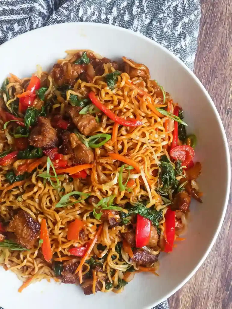Chicken Vegetable Ramen Noodles Recipe 4 Overhead view of chicken vegetable ramen noodles served in a white bowl with red peppers and greens