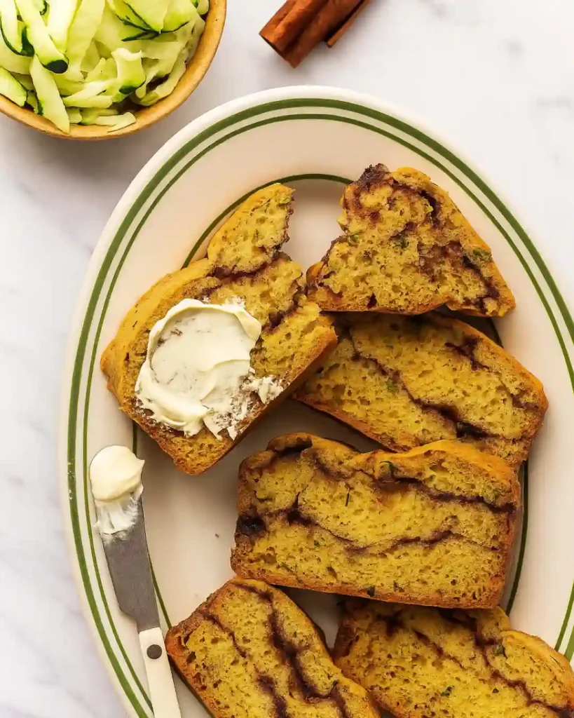 Cinnamon Swirl Zucchini Bread Recipe 3 Slices of Cinnamon Swirl Zucchini Bread on a plate with one spread with butter
