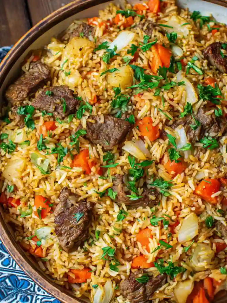 Authentic Beef Plov Recipe 3 Beef Plov dish with fluffy rice, tender beef, carrots, and onions garnished with parsley