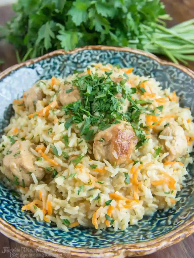Creamy Chicken and Rice Recipe 6 Creamy chicken and rice garnished with parsley in a patterned ceramic bowl