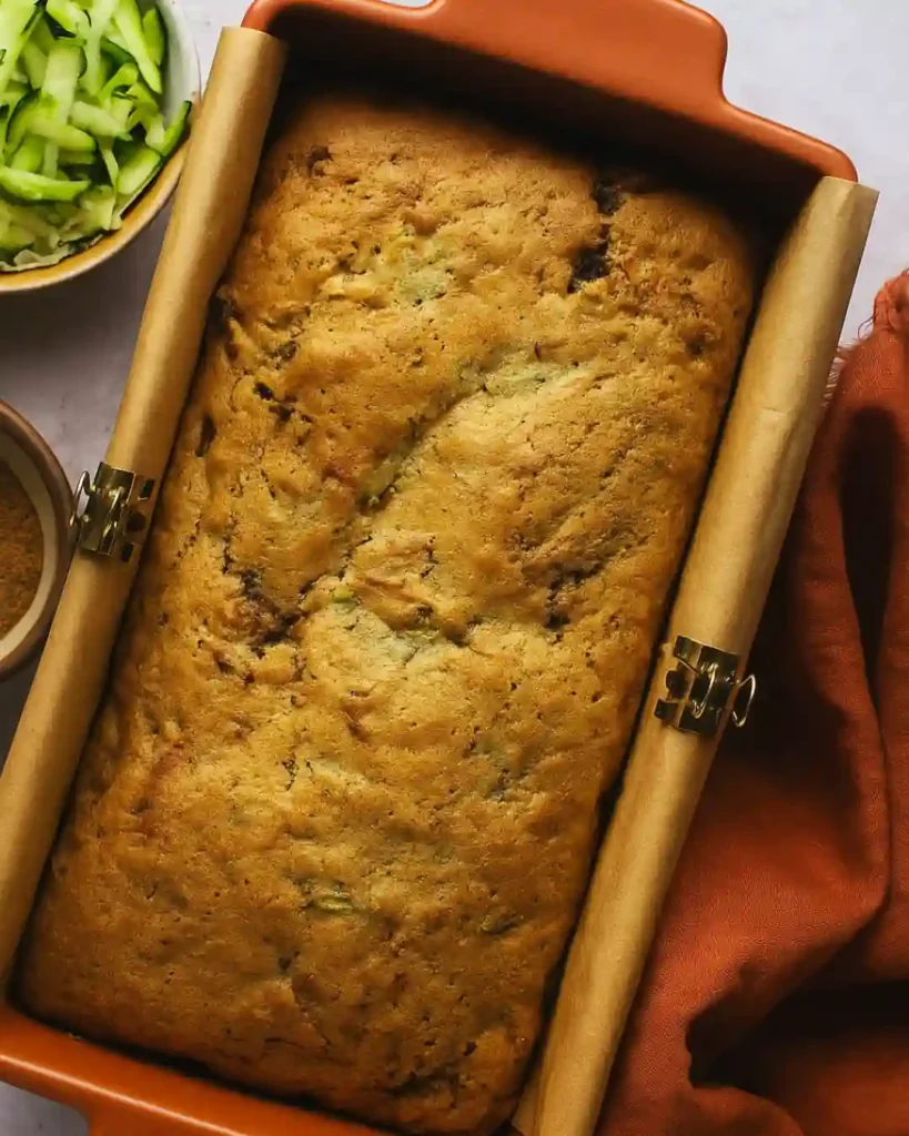 Cinnamon Swirl Zucchini Bread Recipe 2 Whole loaf of Cinnamon Swirl Zucchini Bread in a baking pan lined with parchment paper