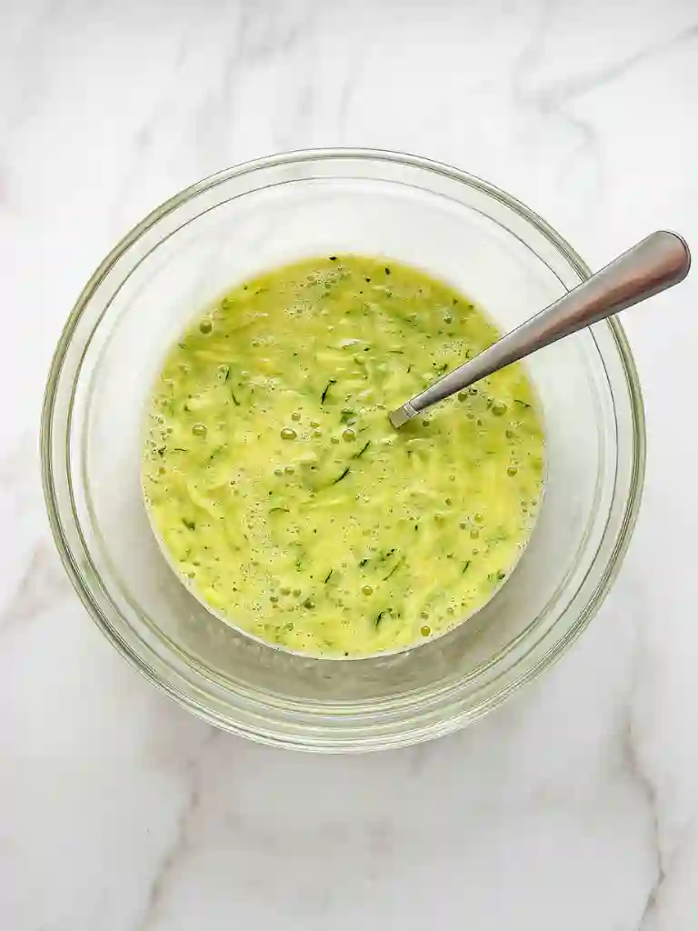 Best Zucchini Bread Recipe 3 Glass bowl with grated zucchini, eggs, and oil mixed for Zucchini Bread Recipe