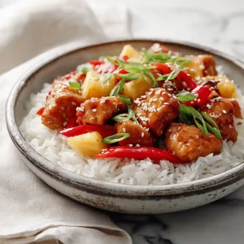 Pineapple Chicken and Rice Recipe 4 Pineapple Chicken and Rice served in a ceramic bowl with red bell peppers, green onions, and sesame seeds