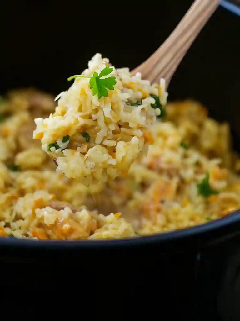 Creamy Chicken and Rice Recipe 5 Close-up of creamy chicken and rice on a wooden spoon with parsley garnish