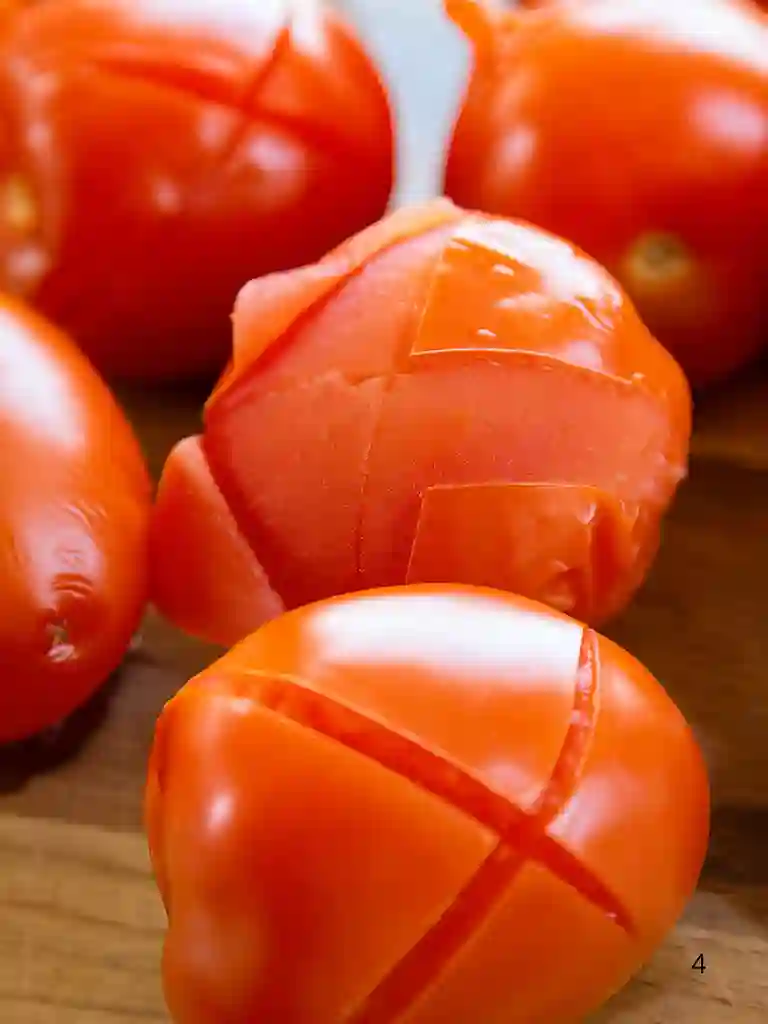 Tomatoes with skin peeling after blanching for Margherita sauce preparation