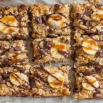Top view of banana oatmeal bars with chocolate drizzle and banana slices on parchment