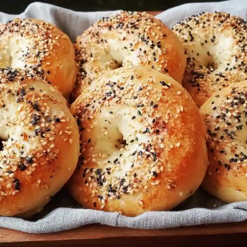 Greek Yogurt Bagels Recipe 4 Golden brown Greek yogurt bagels topped with everything seasoning in a wooden tray
