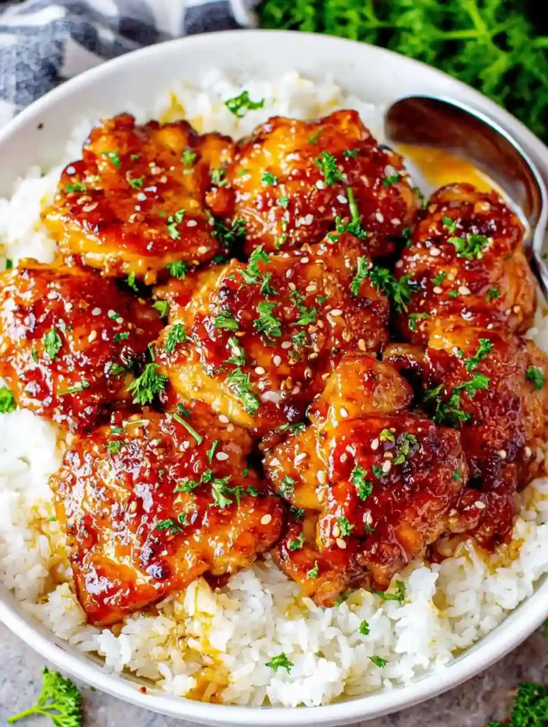 Honey Garlic Chicken Thighs Recipe 3 Honey garlic chicken thighs with sesame seeds and parsley served on white rice in a bowl