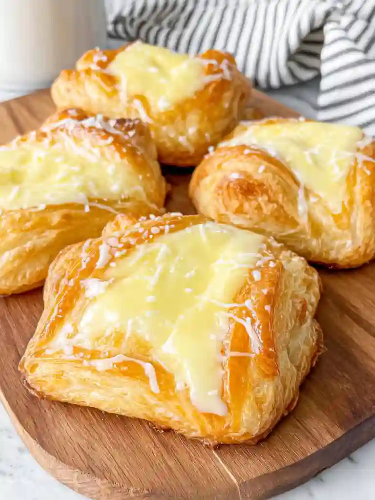 Ultimate Cheese Danish Recipe 2 Cheese Danish pastries with cream filling and icing on a wooden serving board