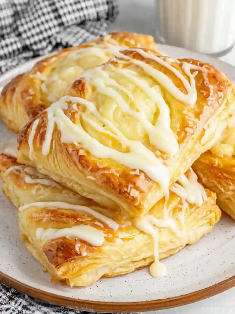 Ultimate Cheese Danish Recipe 3 Cheese Danish pastries with icing drizzle served on a plate
