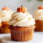 Close-up of pumpkin cupcakes topped with cream cheese frosting and mini fondant pumpkins
