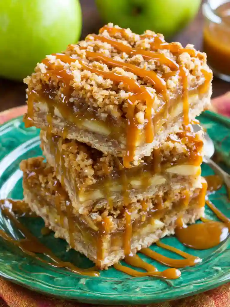Salted Caramel Apple Pie Bars Recipe 4 Salted Caramel Apple Pie Bars stacked on green plate with caramel drizzle and crumb topping