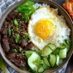Beef Bulgogi Bowls topped with fried egg, cucumber ribbons, and kimchi