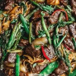 Beef with Oyster Sauce Recipe 10 Beef with Oyster Sauce stir fry with noodles, asparagus, onions, and sesame seeds in a skillet