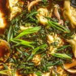 Gyoza soup topped with fresh herbs in a light soy broth