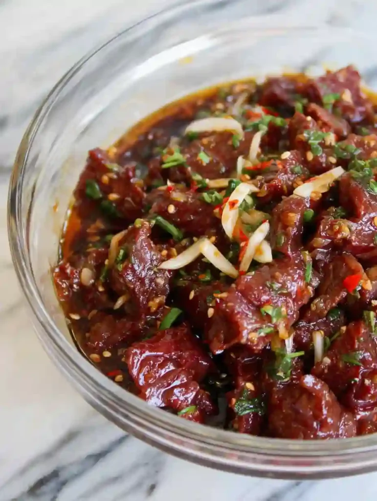 Beef Bulgogi Bowls marinade with sliced beef, garlic, onion, and sesame seeds