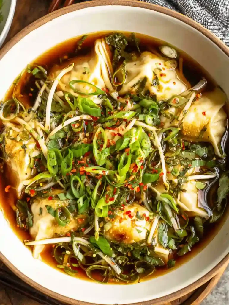 Gyoza soup with chili flakes, spring onions, and dark soy broth