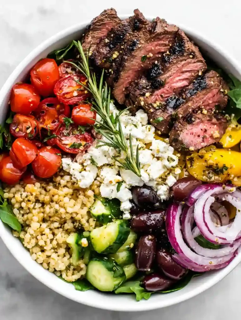 Mediterranean Steak Bowl with grilled sirloin, quinoa, cherry tomatoes, cucumber, olives, red onion, and crumbled feta