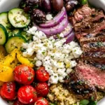 Mediterranean Steak Bowl with grilled sirloin, quinoa, cherry tomatoes, cucumber, olives, feta, and tzatziki sauce.