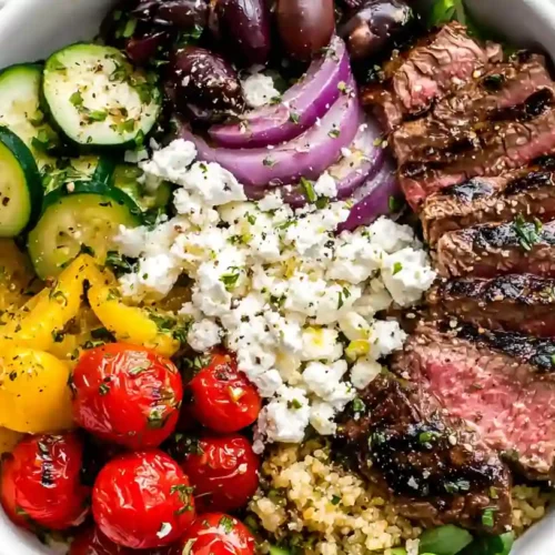 Mediterranean Steak Bowl with grilled sirloin, quinoa, cherry tomatoes, cucumber, olives, feta, and tzatziki sauce.