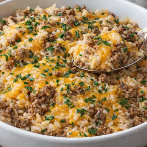cheesy ground beef and rice casserole topped with melted cheddar and fresh parsley in a white bowl
