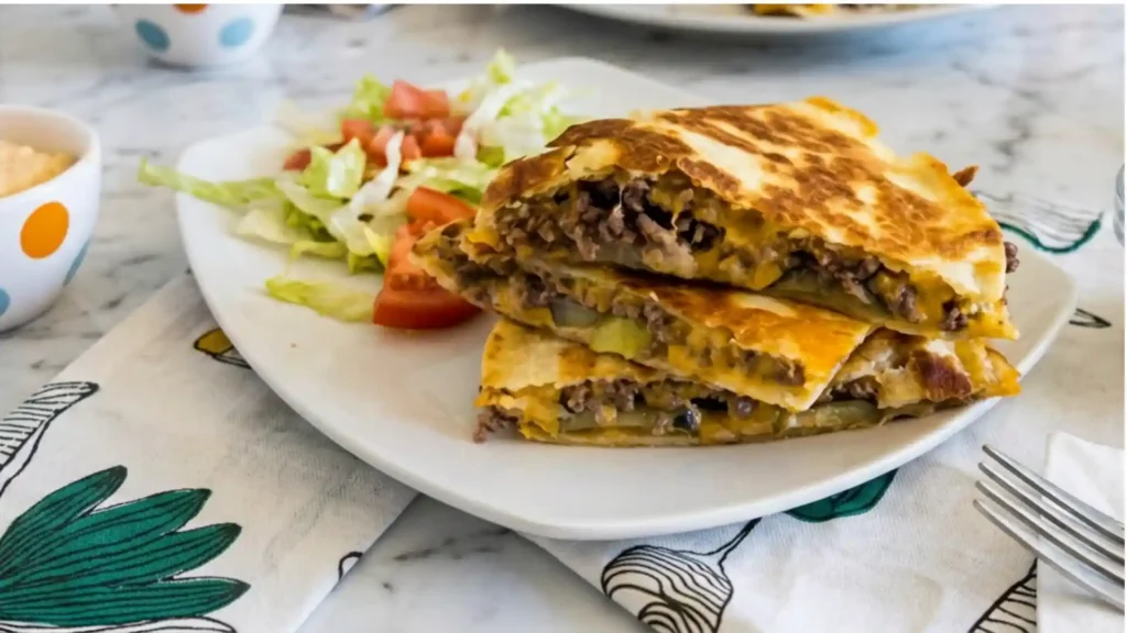 Hamburger Quesadilla sliced and stacked with ground beef and melted cheese on a white plate