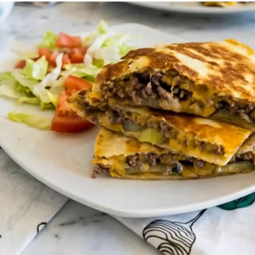 Crispy Hamburger Quesadilla 3 Hamburger Quesadilla sliced and stacked with ground beef and melted cheese on a white plate