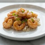 High-Protein Honey Garlic Shrimp 9 High-Protein Honey Garlic Shrimp served on white plate over brown rice with sesame seeds and green onions