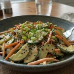 Creamy Asian Cucumber Salad with sesame seeds, carrots, and green onions in a bowl