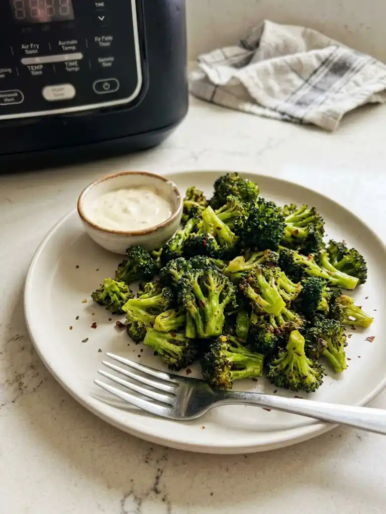 Air fryer broccoli served on plate with dipping sauce