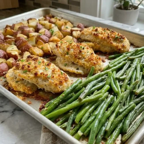 Parmesan Crusted Chicken Sheet Pan Dinner with roasted potatoes and garlic green beans on a baking sheet