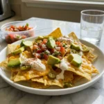 Air Fryer Nachos topped with melted cheese, avocado, jalapenos, sour cream, and fresh pico de gallo