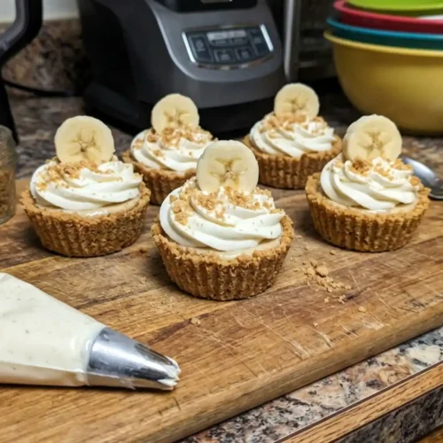 No-bake Mini Banana Cream Pies topped with whipped cream and banana slices on a wooden board