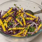 Colorful mango slaw with red cabbage, onions, herbs, and lime dressing